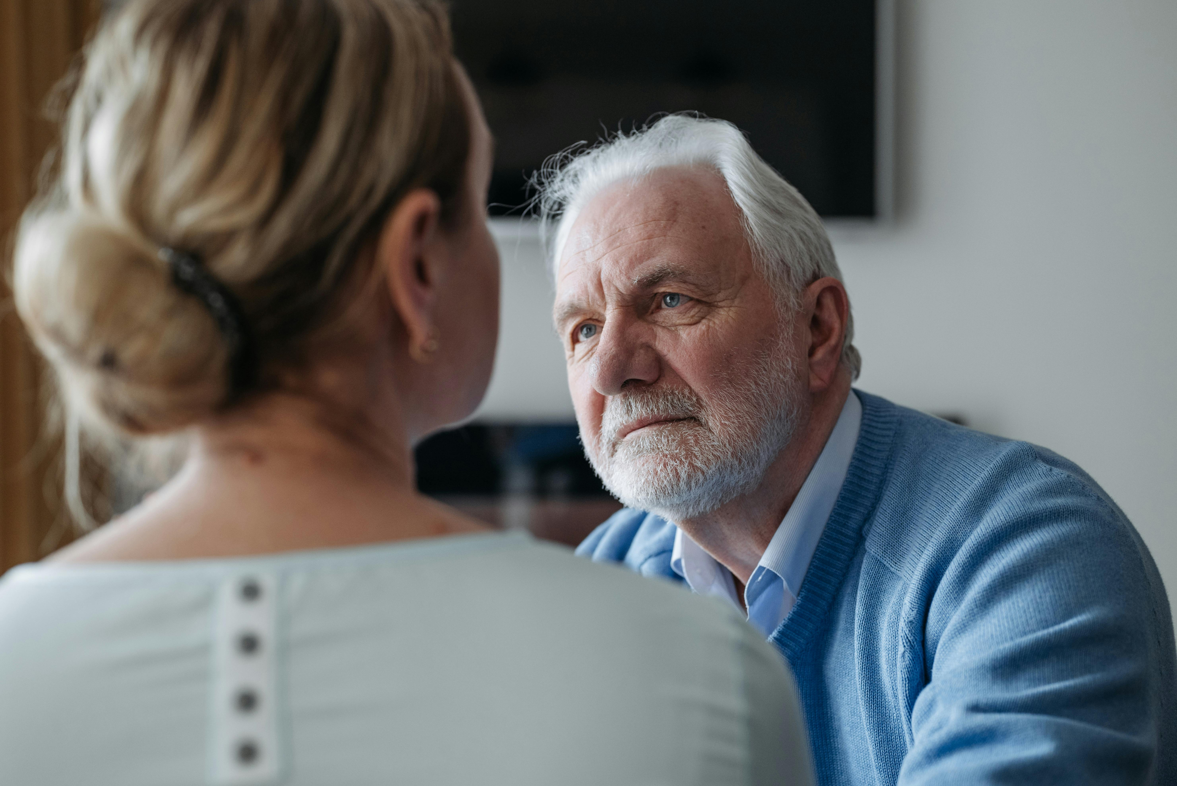 An older man sitting in conversation with a woman during a funeral arrangement meeting.