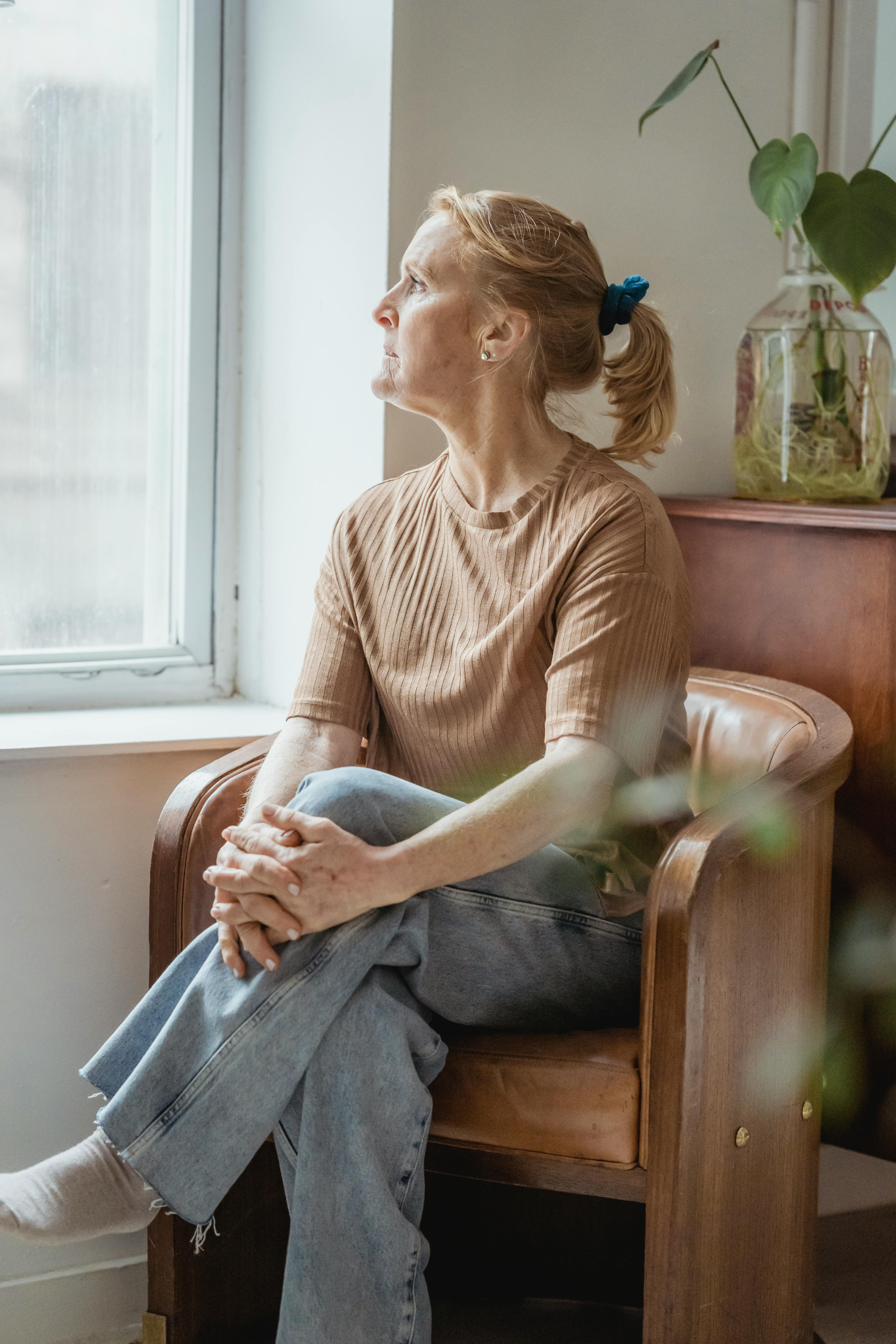 A woman sitting by a window in a calm room.